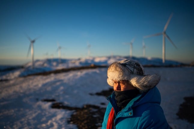 Pictured is a reindeer herder surrounded by wind farms. 